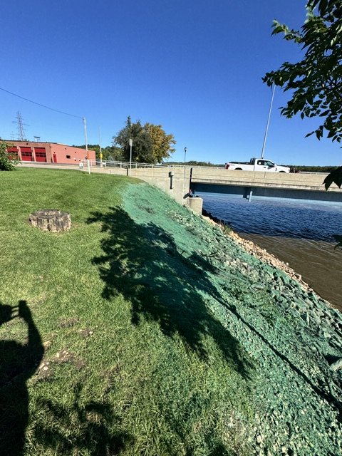 Green hydromulch on a steep riverbank embankment near a bridge